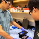 WSU Professor Lei Li and graduate student Yu-Chung Chang (l-r) test the new smartphone that detects 12 common viral and bacterial infectious diseases. Credit: Washington State University